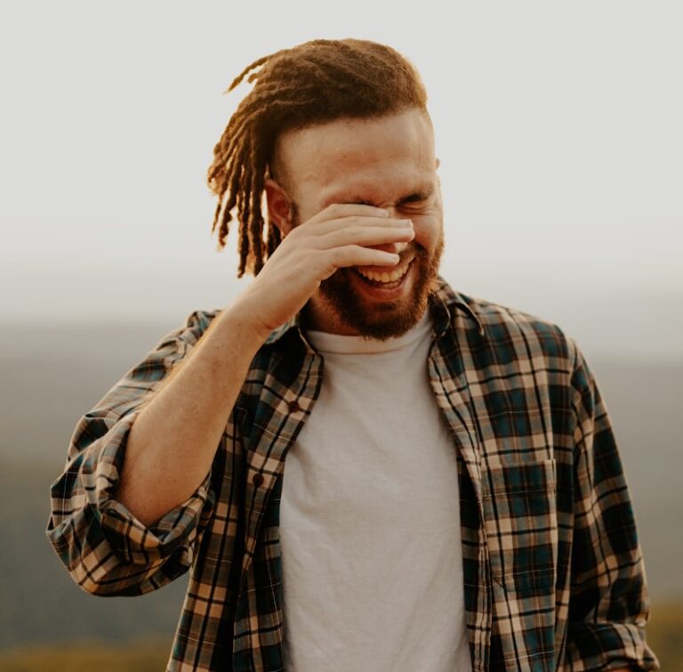 man in black and white plaid dress shirt covering his face with his hand